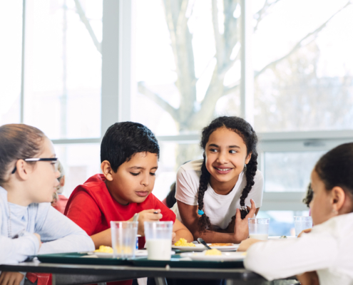 Children sitting around a cafeteria table talking