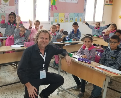 Breakfast club of canada man kneeling in a classroom in Tunisia