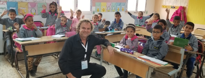 Breakfast club of canada man kneeling in a classroom in Tunisia