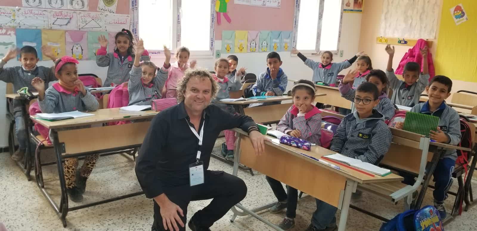 Breakfast club of canada man kneeling in a classroom in Tunisia