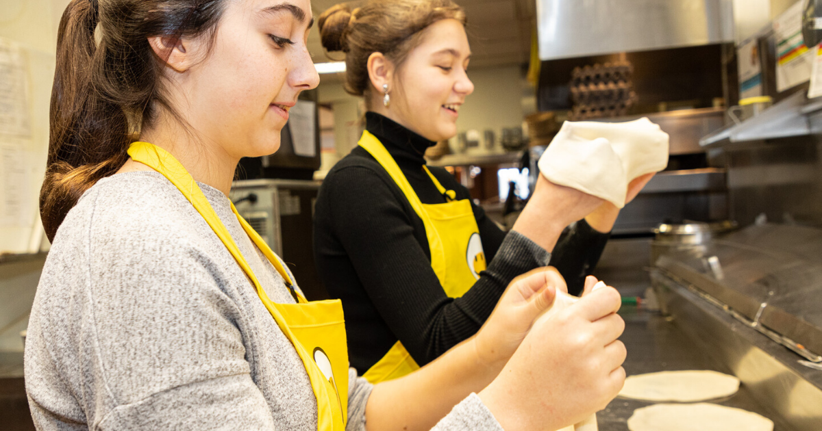 2 young women making pitas in a kitchen