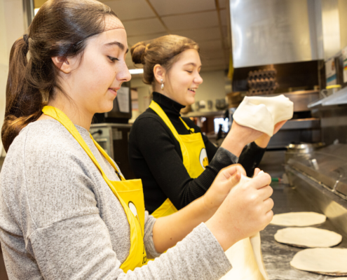 2 young women making pitas in a kitchen