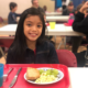 Little girl smiling and enjoying her breakfast of grapes bread and eggs