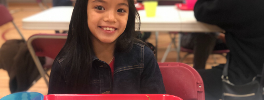 Little girl smiling and enjoying her breakfast of grapes bread and eggs