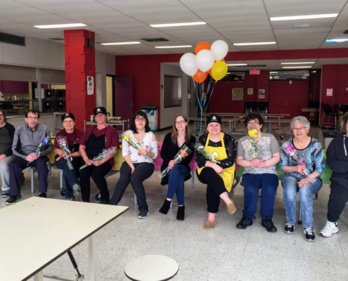 Volunteers sitting in a line with flowers and baloons