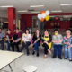 Volunteers sitting in a line with flowers and baloons