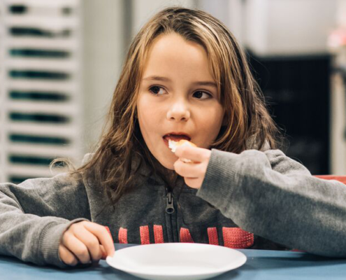 Child with long hair eating a piece of bread