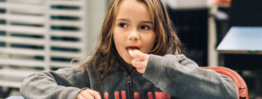 Child with long hair eating a piece of bread