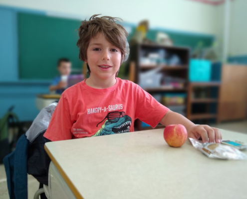 child sitting at desk with an apple