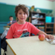 child sitting at desk with an apple