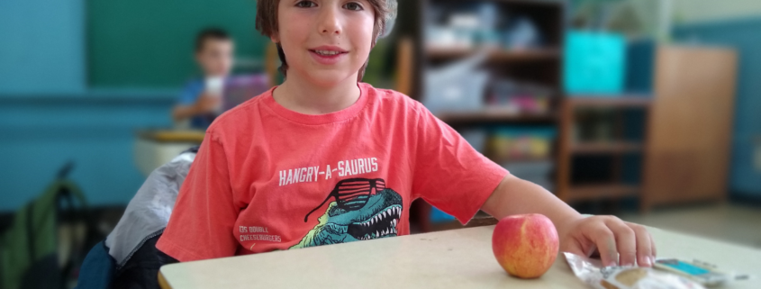 child sitting at desk with an apple