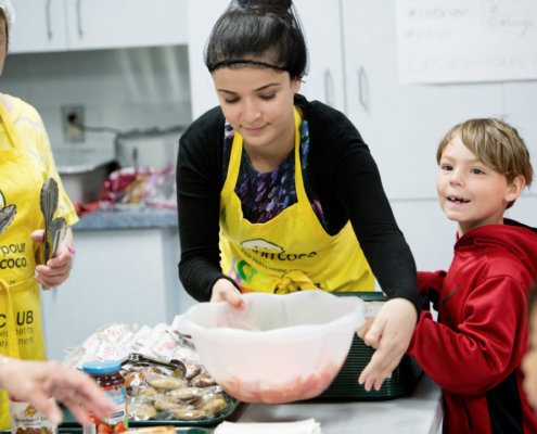 Volunteers with child making breakfast