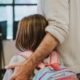 Daughter with a backpack on and father with hand around her