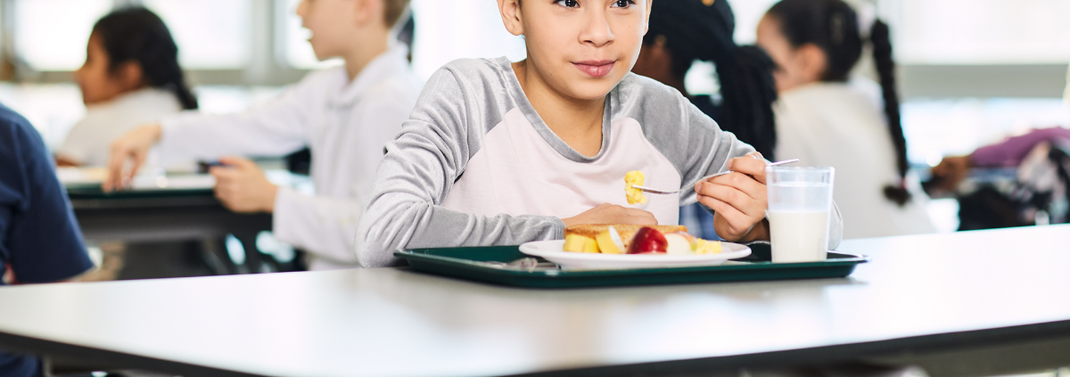 Child eating breakfast in cafeteria
