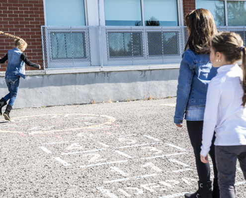 3 children playing hopscotch on a school playground